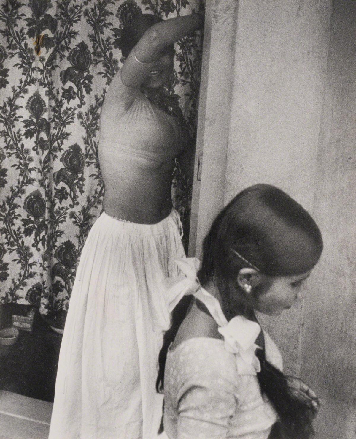 Leon Levinstein, Untitled (woman in front of curtain with arm up India), not dated.