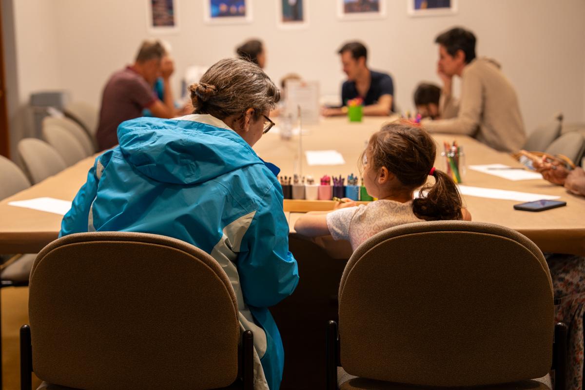 Adults and children sitting at a table with art supplies