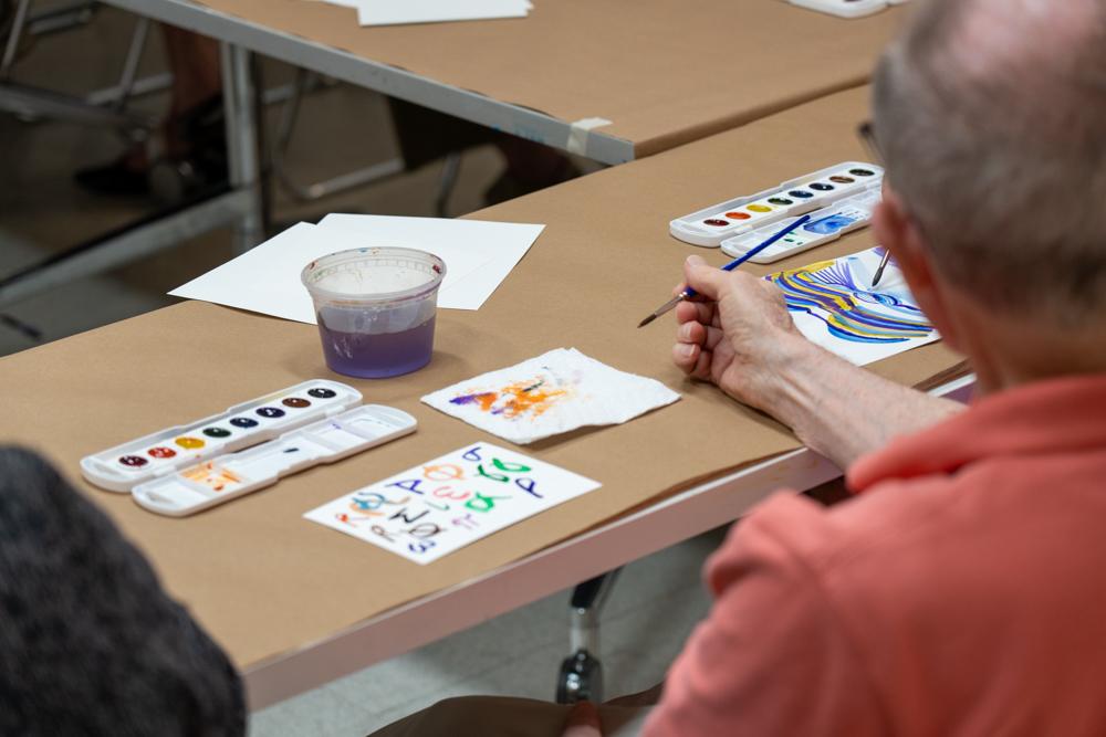Photo of an older adult painting watercolor at a table