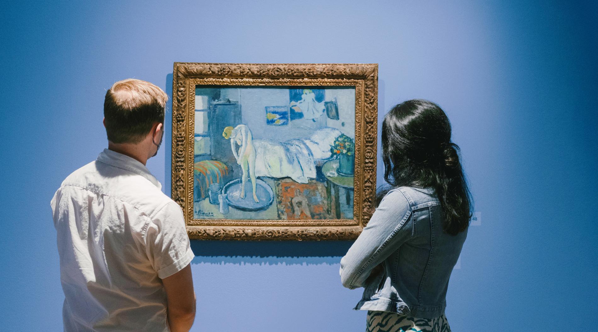 Photograph of two people looking at Picasso's The Blue Room