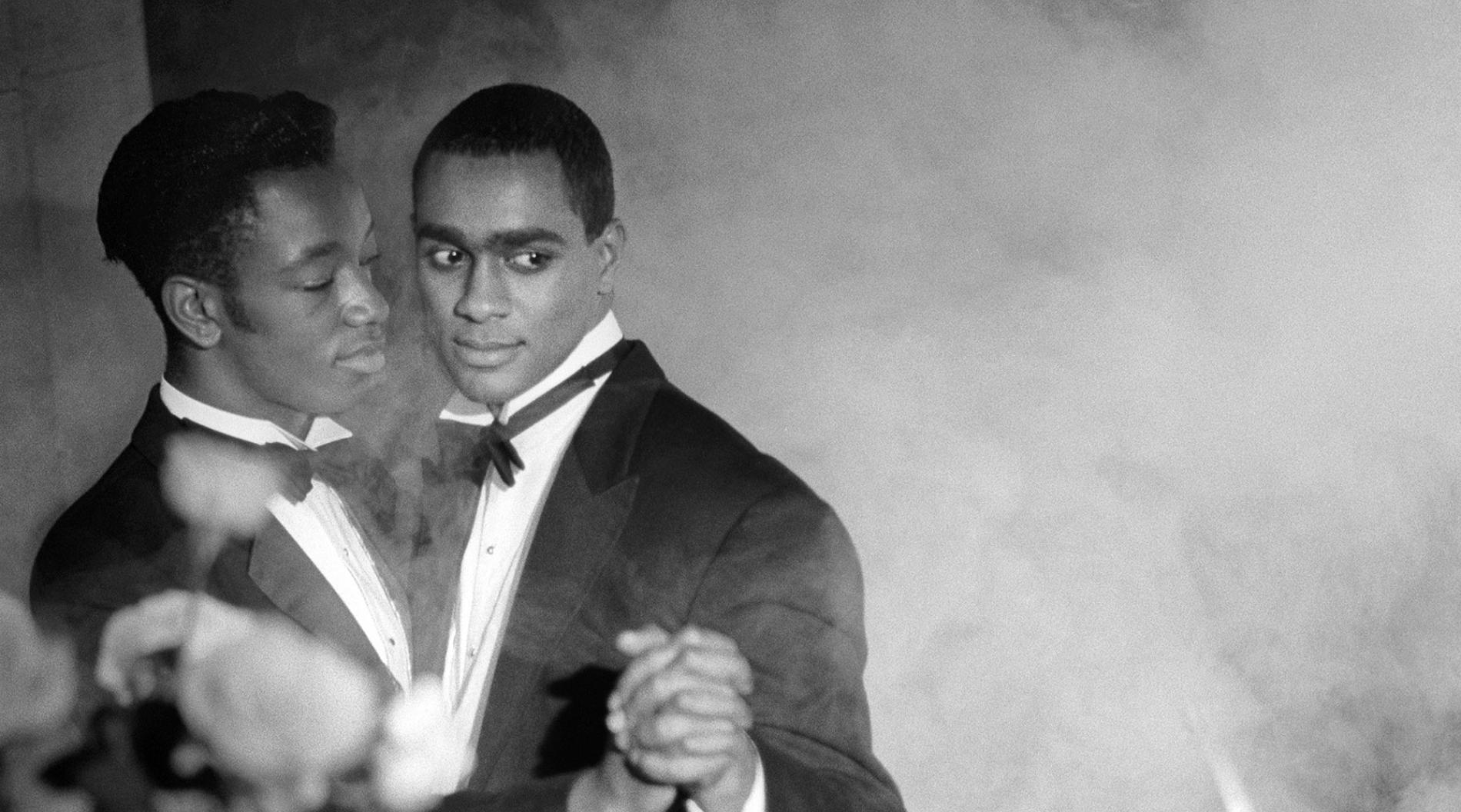 Black-and-white photograph of black men in tuxedos dancing