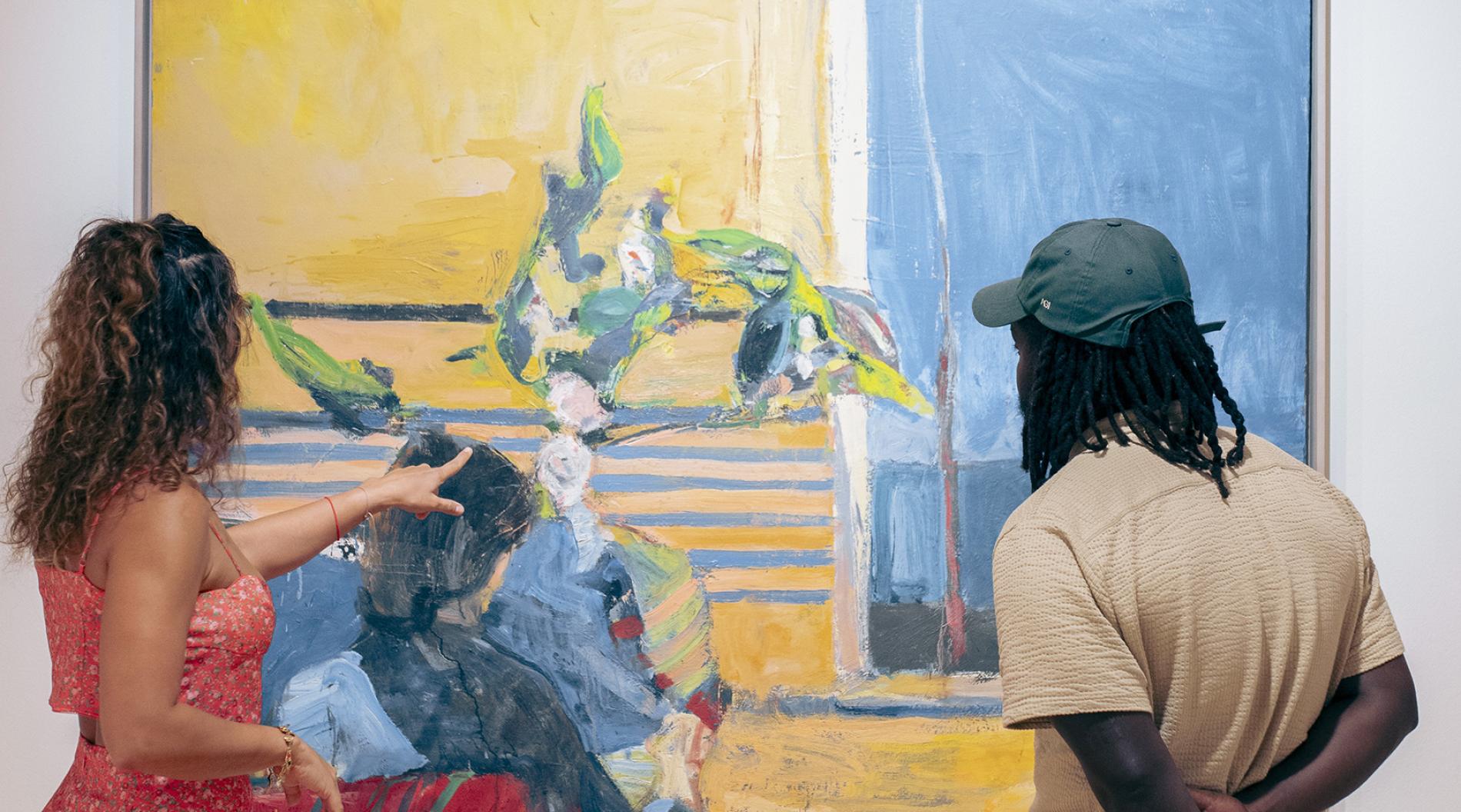 Two people looking at a large painting on a wall