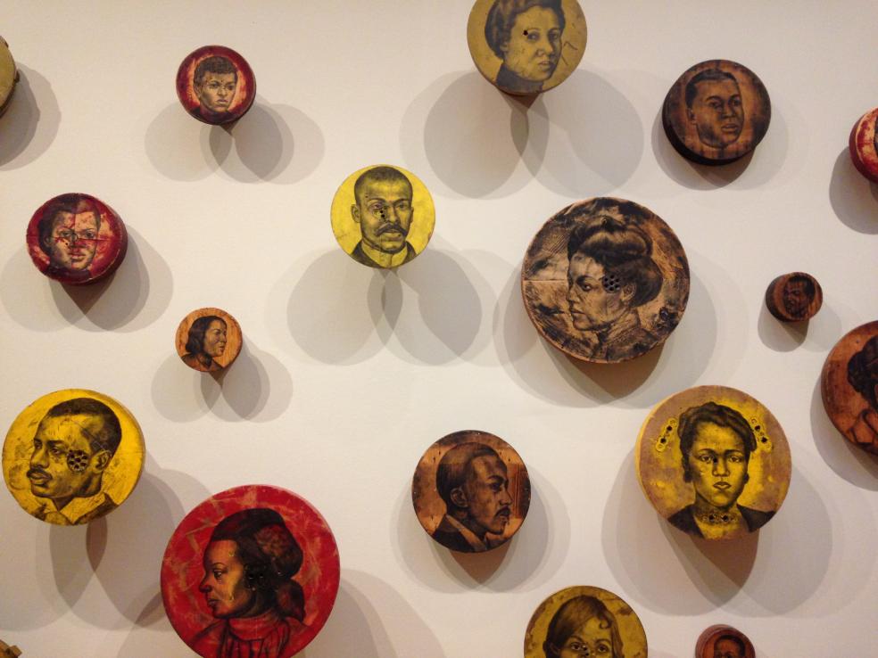 Photo of Whitfield Lovell's Rive Barton Series (2004) of African American portrait drawn on round wood panels