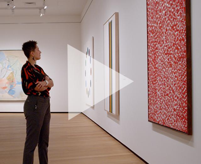 A person standing in front of an Alma Thomas painting in a museum gallery