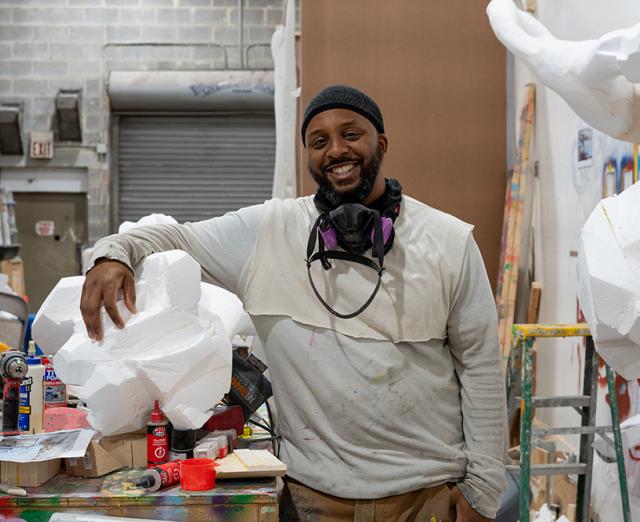 Wesley Clark in his studio smiling with his artwork