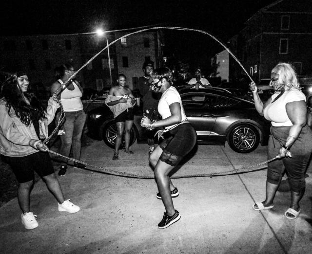 Black and white photograph of women playing double dutch on the street