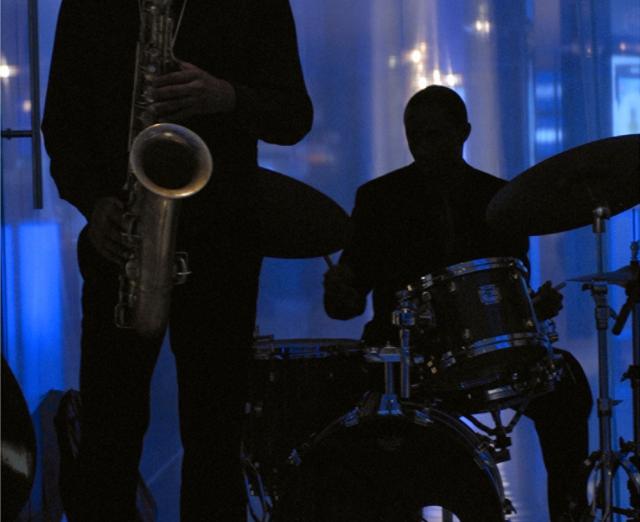 Photograph of two people playing musicians with blue background