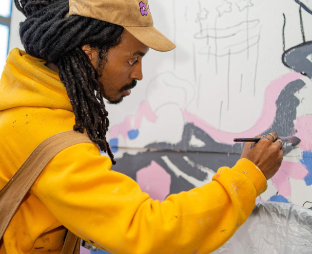 Photograph of Chris Pyrate painting a mural