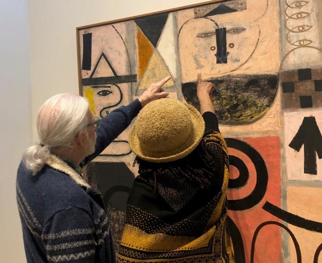 Photograph of two people pointing at an artwork
