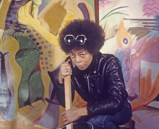 Vivian Browne kneeling in front of her paintings