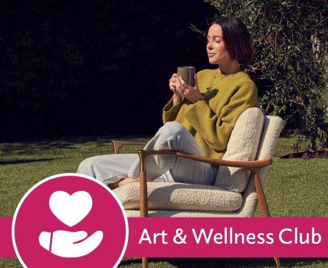 Eve Lewis meditating holding a mug sitting on a chair on a lawn