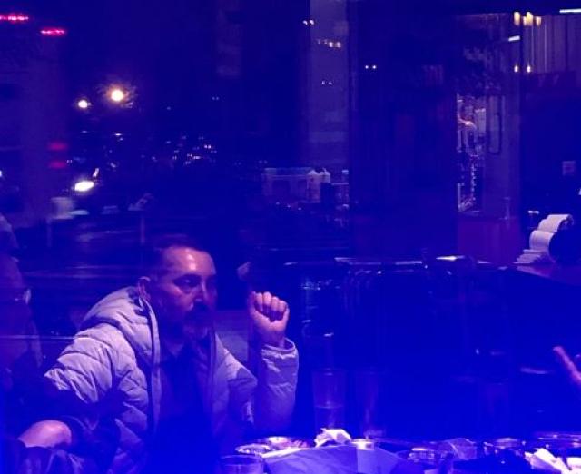 Photograph with a blue tint of a man sitting at a table