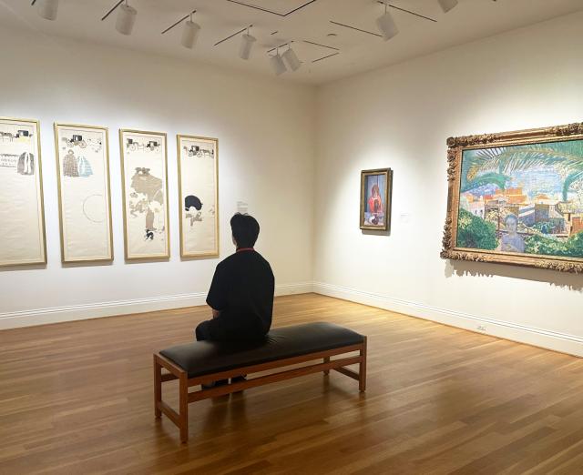 Installation view of three works by Bonnard with a bench and a guest in the middle of the room