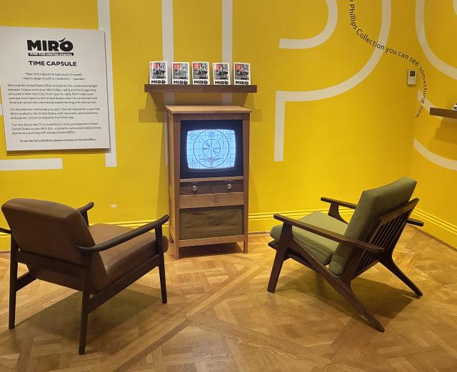 Two chairs in front of a retro tv against a yellow wall 