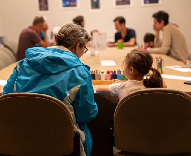 Adults and children sitting at a table with art supplies