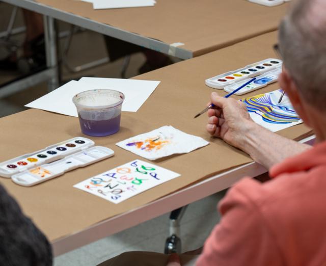 Photo of an older adult painting watercolor at a table