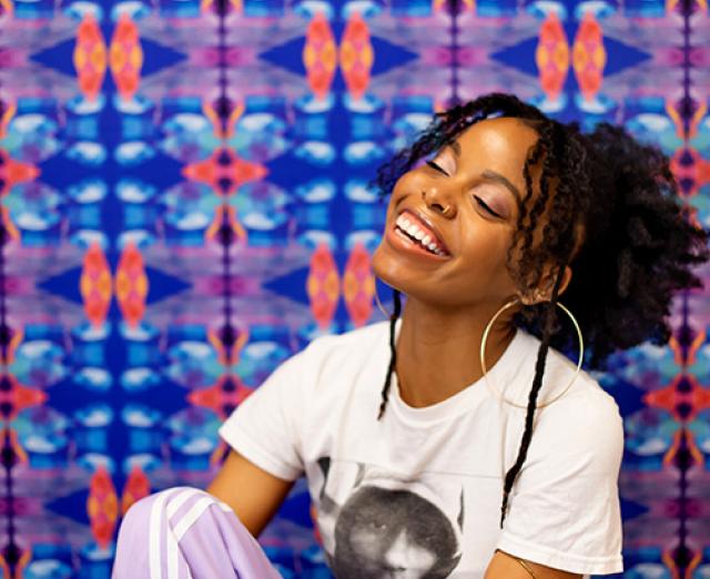 Photo of Aliana Grace Bailey smiling in front of a colorful background