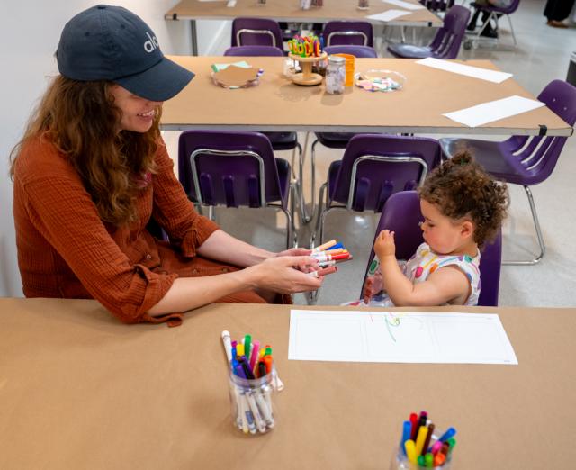 An adult and a child in the Art Workshop coloring with markers