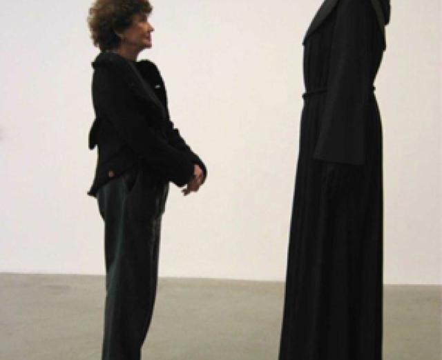 Anita Reiner standing in front a human figure cloaked in black.
