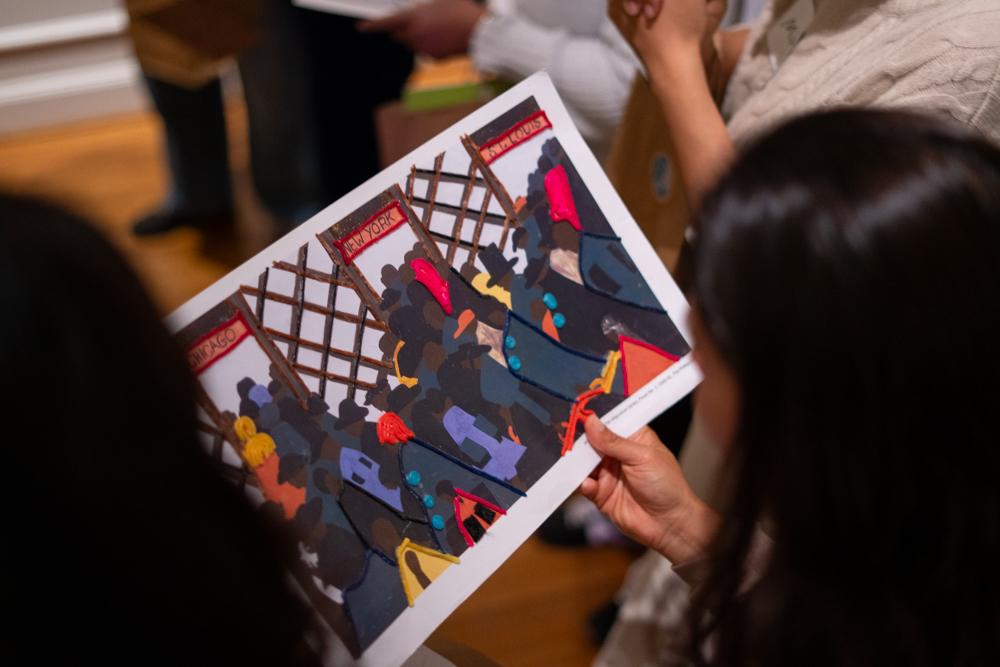 Someone holding a reproduction of Jacob Lawrence's Migration Series Panel 1