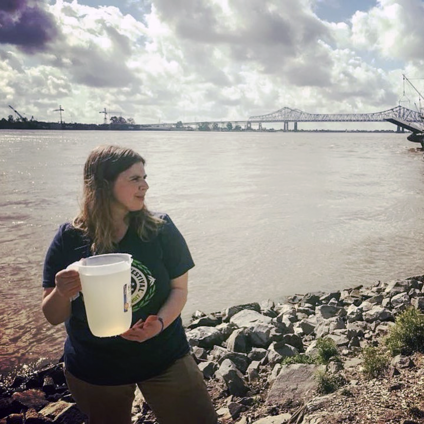 A woman holding a pitcher of water by a river