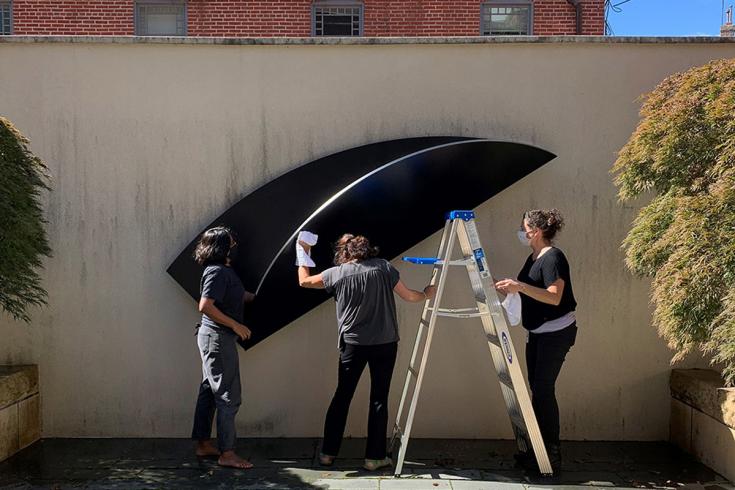 Conservators clean a sculpture in the courtyard