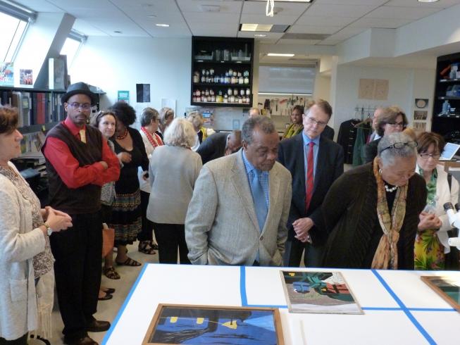 A group of people in the Conservation Studio looking at Jacob Lawrence's Migration Series
