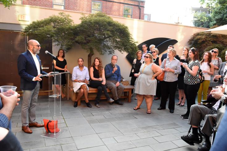 Photograph of a crowd standing in the Phillips courtyard, with a man standing at a podium 