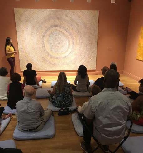 Photograph of group meditation in front of a large painting.