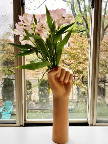 Photograph of a vase in the shape of a fist holding flowers 