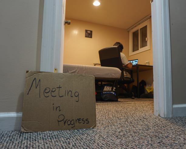 Photograph of a handwritten sign that reads "Meeting in progress" outside of a office door