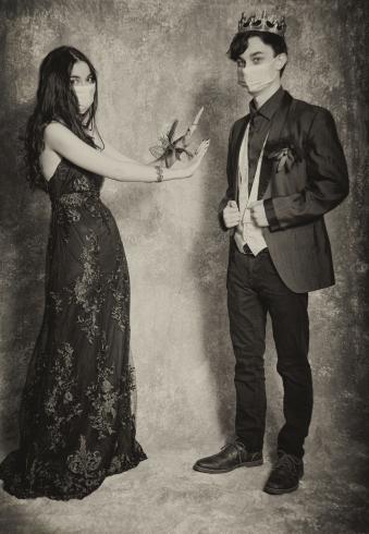 Sepia photo of two people dressed up in prom attire, with masks on, not touching