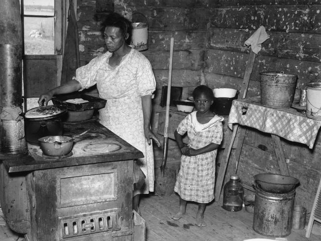 Black and white photograph of a kitchen on a Southeast Missouri Farm with a parent and child.