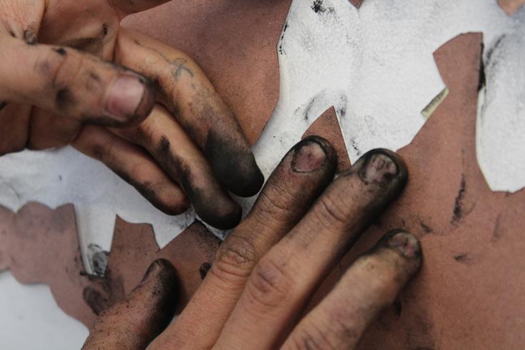 Photograph of hands with black stairs on fingers creating something