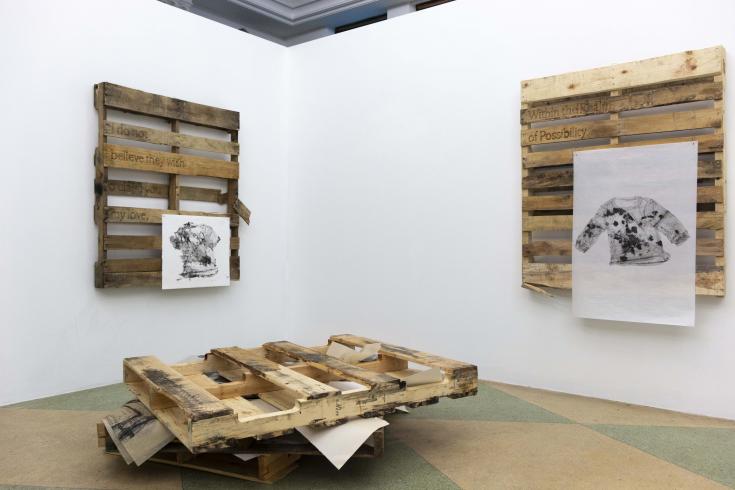 Photograph of an art installation with three pieces made of wood with black and white drawings