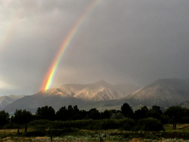 Color photograph. A mountainous countryside with a rainbow.