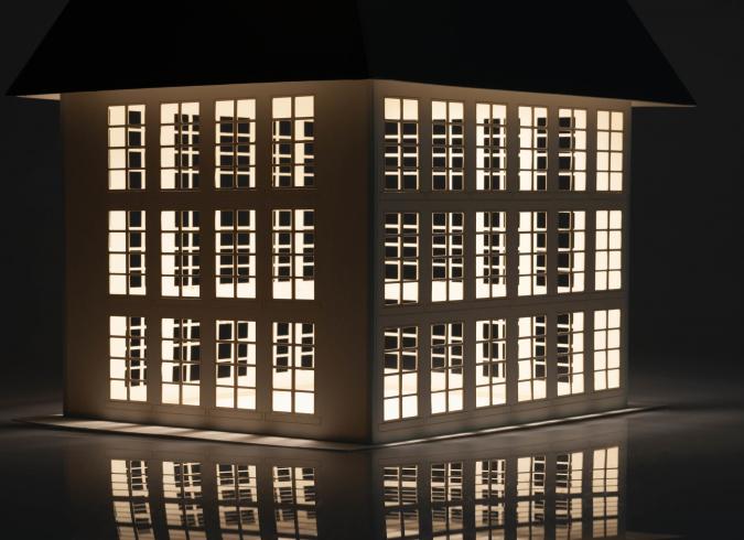 Color photograph. An architectural model with many windows lit from the interior.
