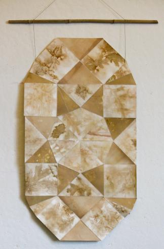 Paper quilt. A hanging design of paper sewn into a geometric pattern and printed with earthy traces of leaves.