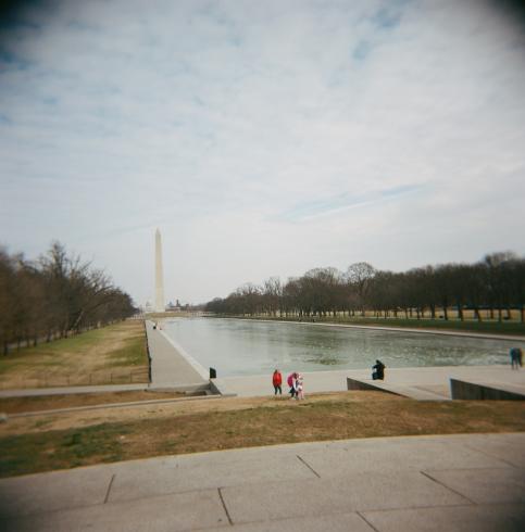Image of people setting by a body of water next to the Washington Monument 