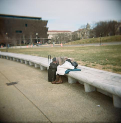 Image of person sleeping on a bench outside of the African American History and Culture Museum 