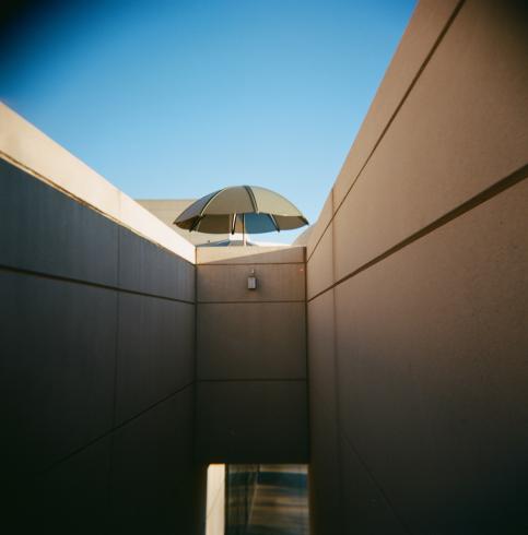 Image of an angular building with a black umbrella in the center 