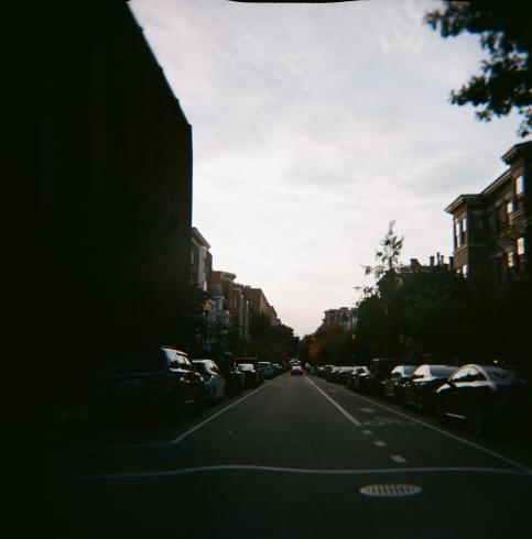 Image of an open street with cars parked on both sides in a neighborhood 