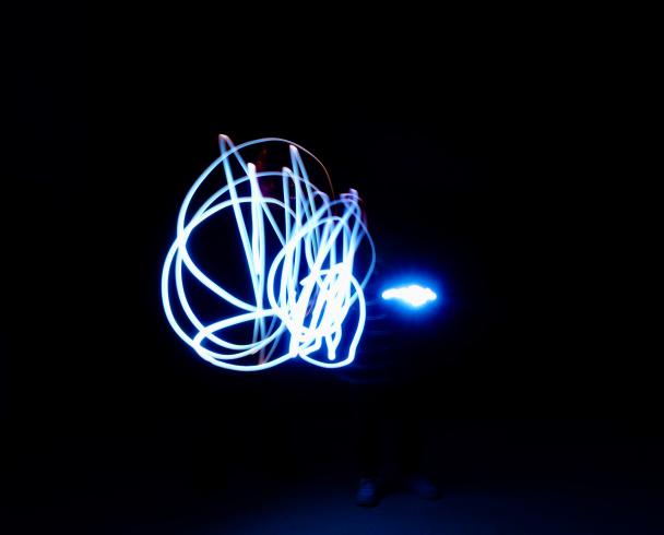 Photograph highlighting the silhouette of student using neon lights. 
