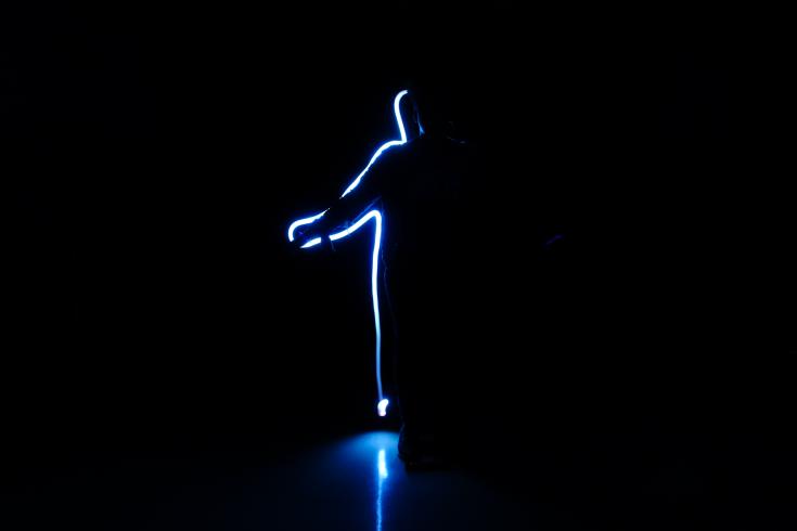 Photograph highlighting the silhouette of student using neon lights. 