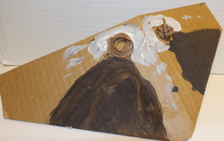 Triangular cardboard piece with yarn eyes and brown wings.