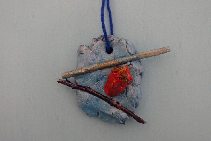 Clay mobile with two sticks and a painted acorn.