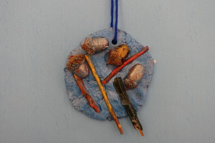 Clay mobile with painted sticks and acorns.