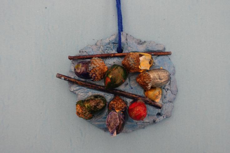 Clay mobile with painted acorn and sticks.