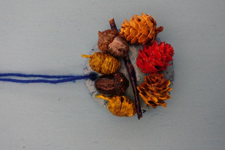 Clay mobile with painted acorns and pinecones.