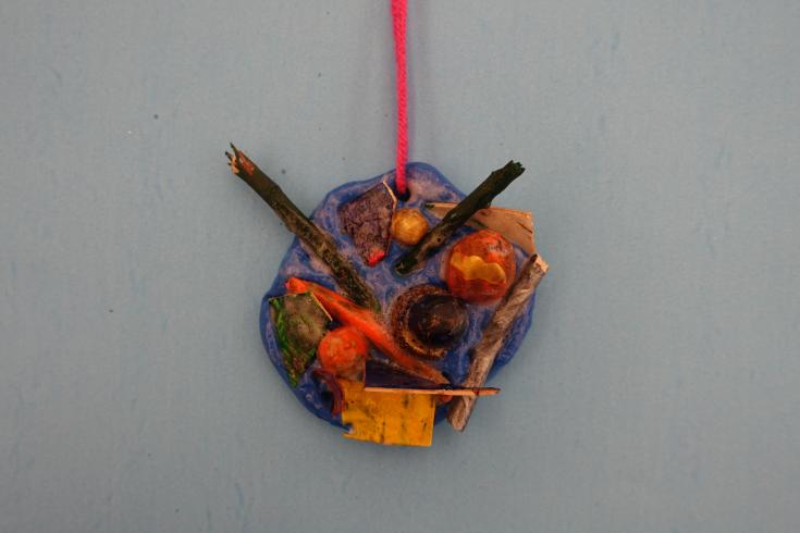 Clay mobile with painted acorns and sticks.